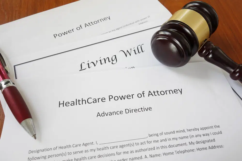 Living will and healthcare power of attorney documents with gavel and pen on desk.